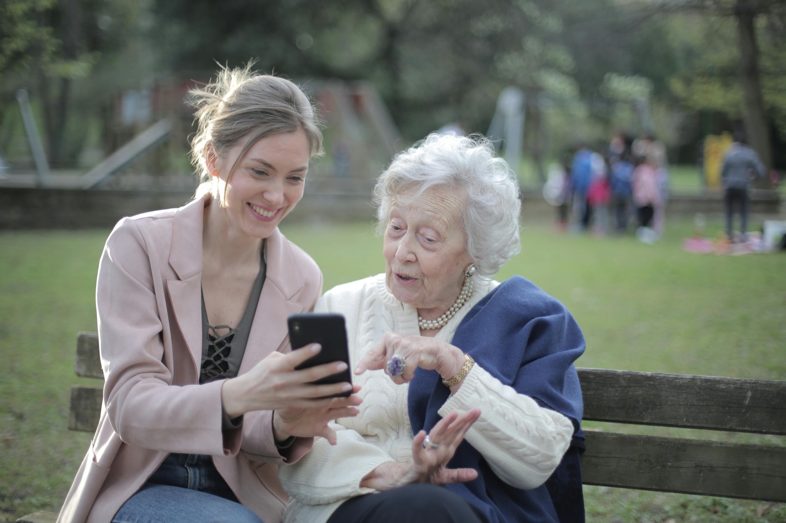 Senhora idosa e uma familiar sentadas em um banco, conversando